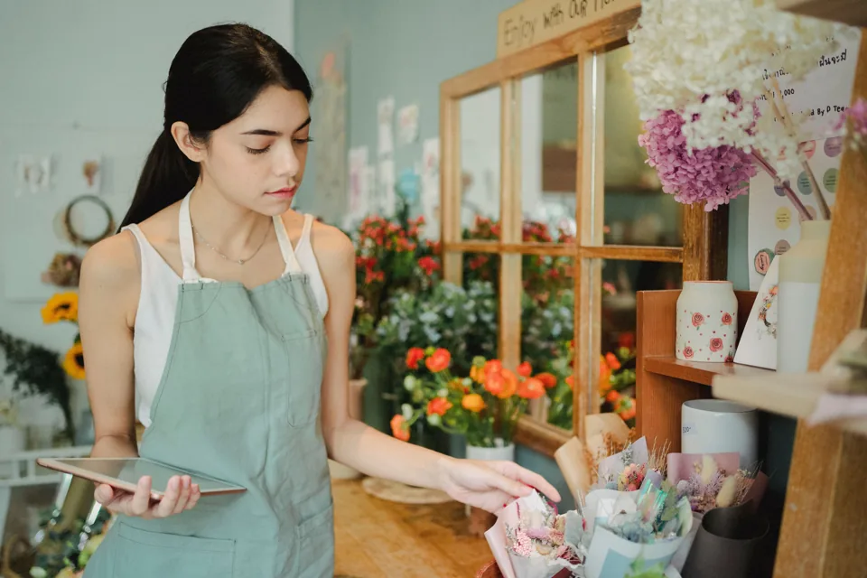 A florist tending to flowers in a sunlit shop.